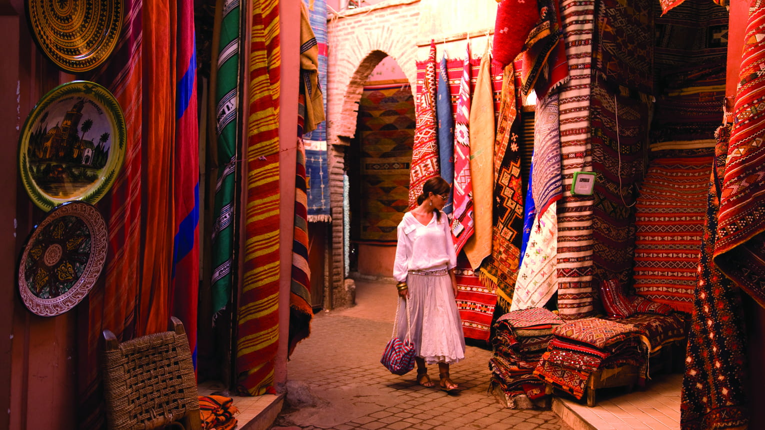 Traveller browsing handwoven rugs in a Marrakech souk